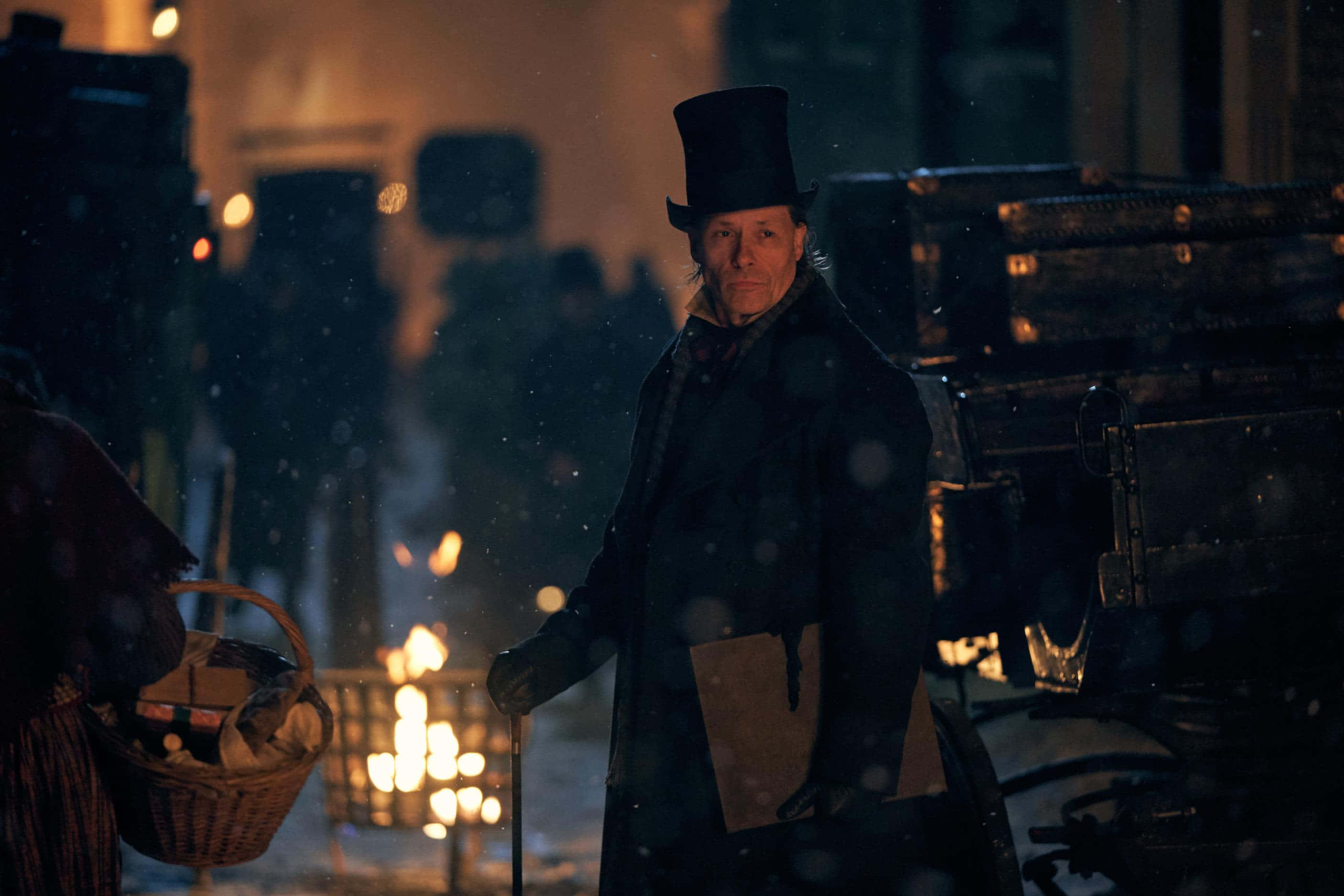 ایک آدمی جو ٹوپی پہنے اور ٹوکری لے کر برف میں چل رہا ہے وال پیپر