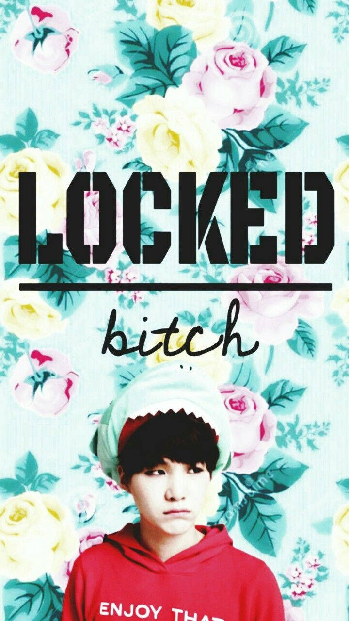 بی ٹی ایس سوگا پھولوں کے پس منظر میں جس پر لکھا ہے "locked bitch"۔