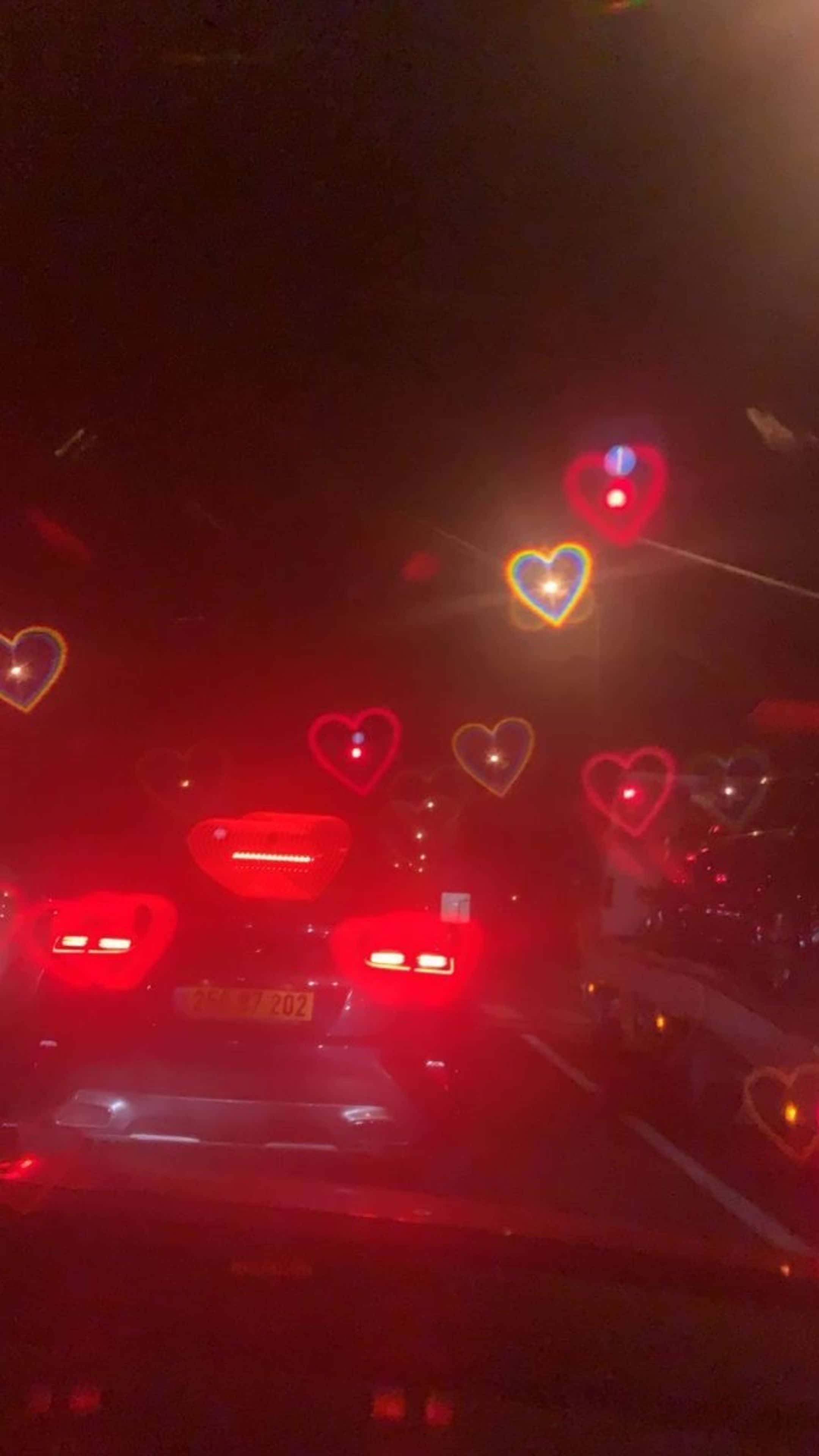 رات کو سڑک پر چلتی گاڑی جس کی ونڈشیلڈ پر دل ہیں وال پیپر