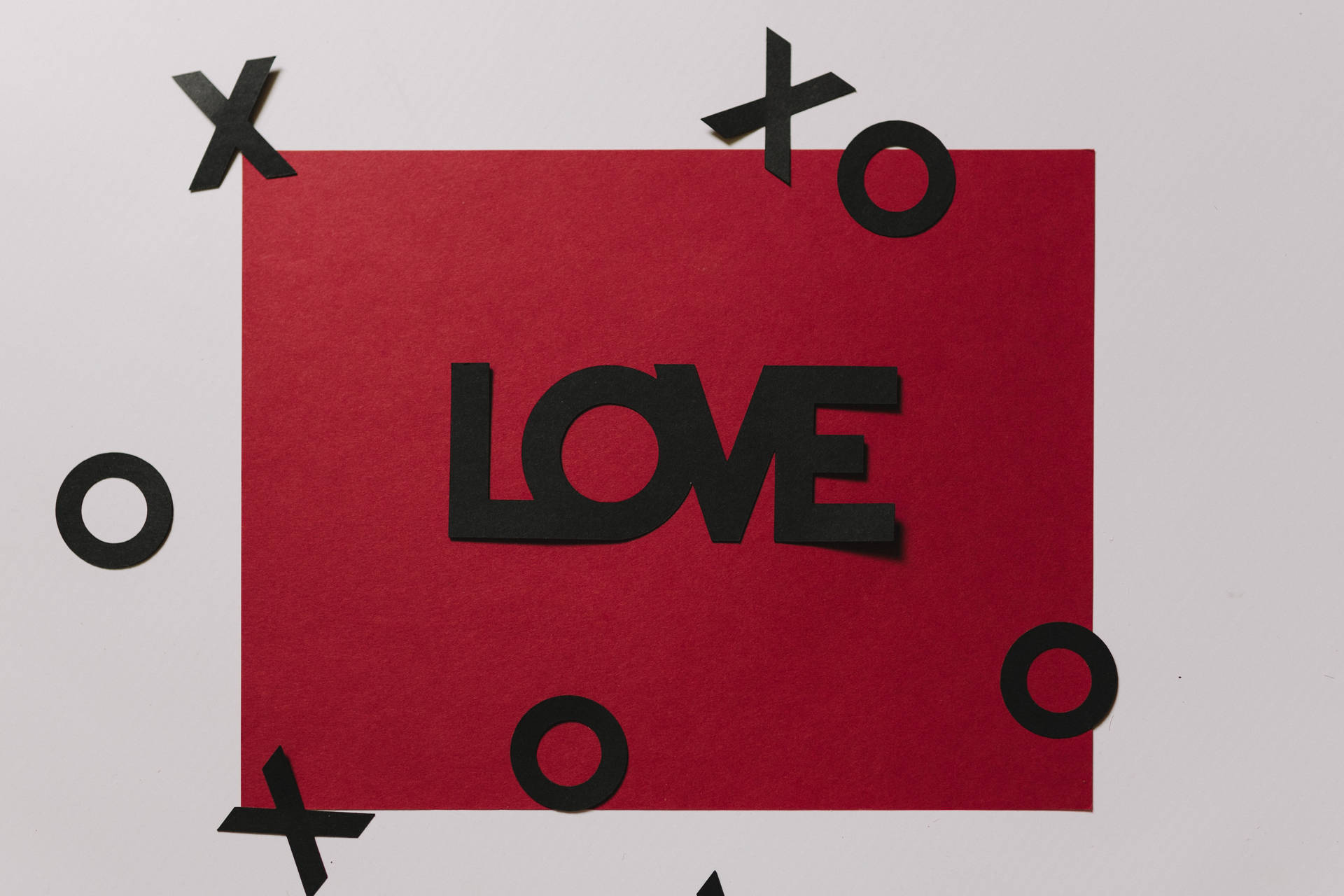 سرخ محبت کا خط جس پر سیاہ میں "محبت" لکھا ہے اور سفید سطح پر XOXO کے تیرتے کٹ آؤٹ ہیں۔
